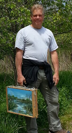 Person holding a painting outdoors in a natural setting.