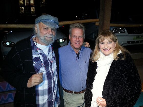 Three smiling adults posing outdoors at night